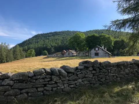 Le baite dell'alpe Pescia oltre un muro a secco