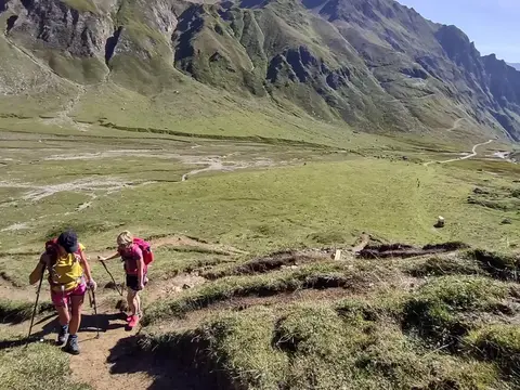Due escursioniste in salita sopra un'ampia piana verde