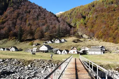 Il ponte di legno e le baite della val Loana in autunno