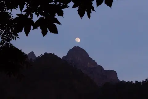 La luna sopra le cime al tramonto