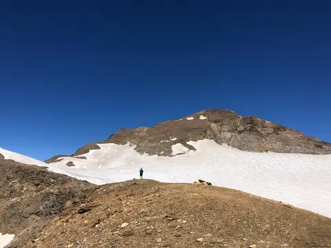 Un escursionista ai margini del nevaio sotto la vetta