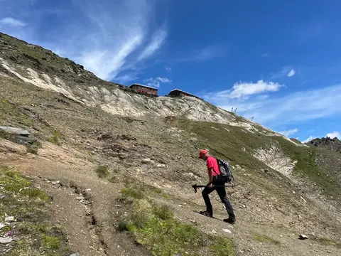 Un'escursionista in salita verso il rifugio in cima al pendio