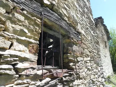 La finestra con l'inferriata di una baita in pietra