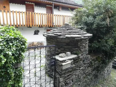 Un piccolo edificio circolare in pietra con il tetto in piode