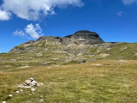 Un ometto di pietre sul pianoro, con la cima del Cistella sullo sfondo