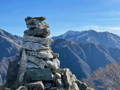 Un grande ometto di pietre sulla cresta, davanti alle montagne