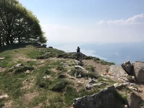 La cima del monte Faiè con un ometto di pietre e il lago sullo sfondo